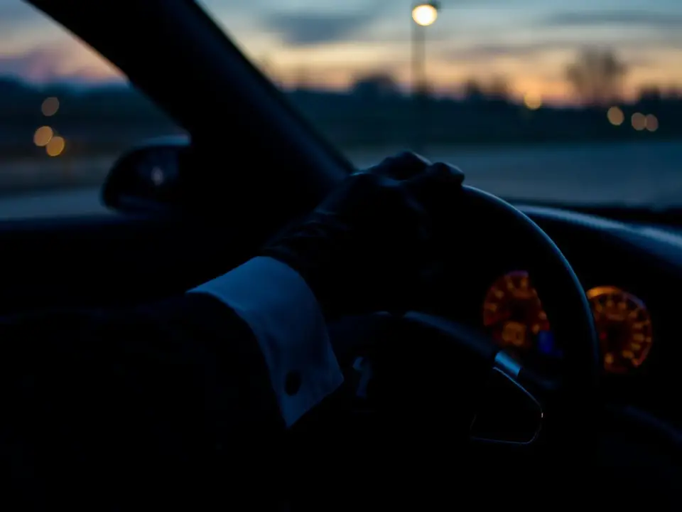 Professional chauffeur at the wheel at dusk